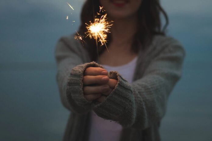 A woman holding a sparkler at night, symbolizing investing in the Canadian stock market and financial growth.